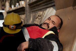 Obrero de la construcción descansando sobre un cartón en el suelo, simbolizando la precariedad y falta de condiciones dignas.