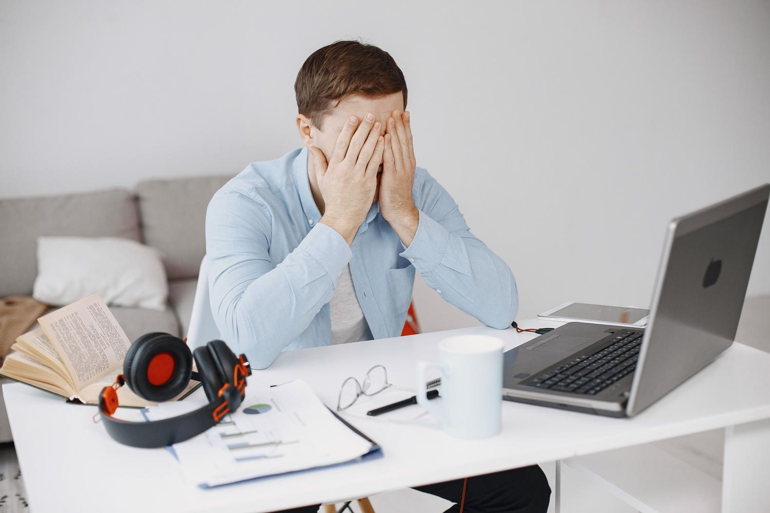 Stressed man working in his home office, representing the uncertainty and pressure of the modern job market. Stressed man working in his home office, representing the uncertainty and pressure of the modern job market.