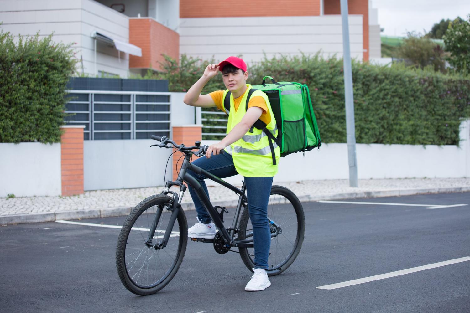 Food delivery person on a bicycle in an urban area, representing the platform economy and bogus self-employed workers. Food delivery person on a bicycle in an urban area, representing the platform economy and bogus self-employed workers.