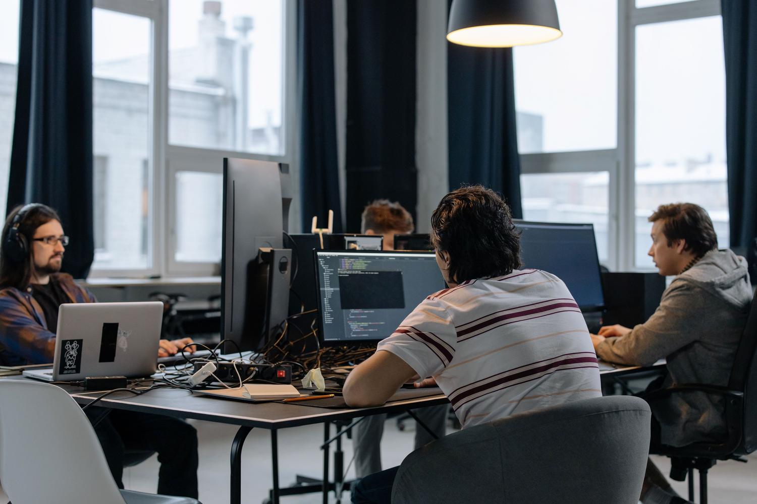 Equipo de desarrolladores trabajando juntos en computadoras en una oficina tecnológica moderna, representando la colaboración corporativa y el trabajo en paralelo. Equipo de desarrolladores trabajando juntos en computadoras en una oficina tecnológica moderna, representando la colaboración corporativa y el trabajo en paralelo.