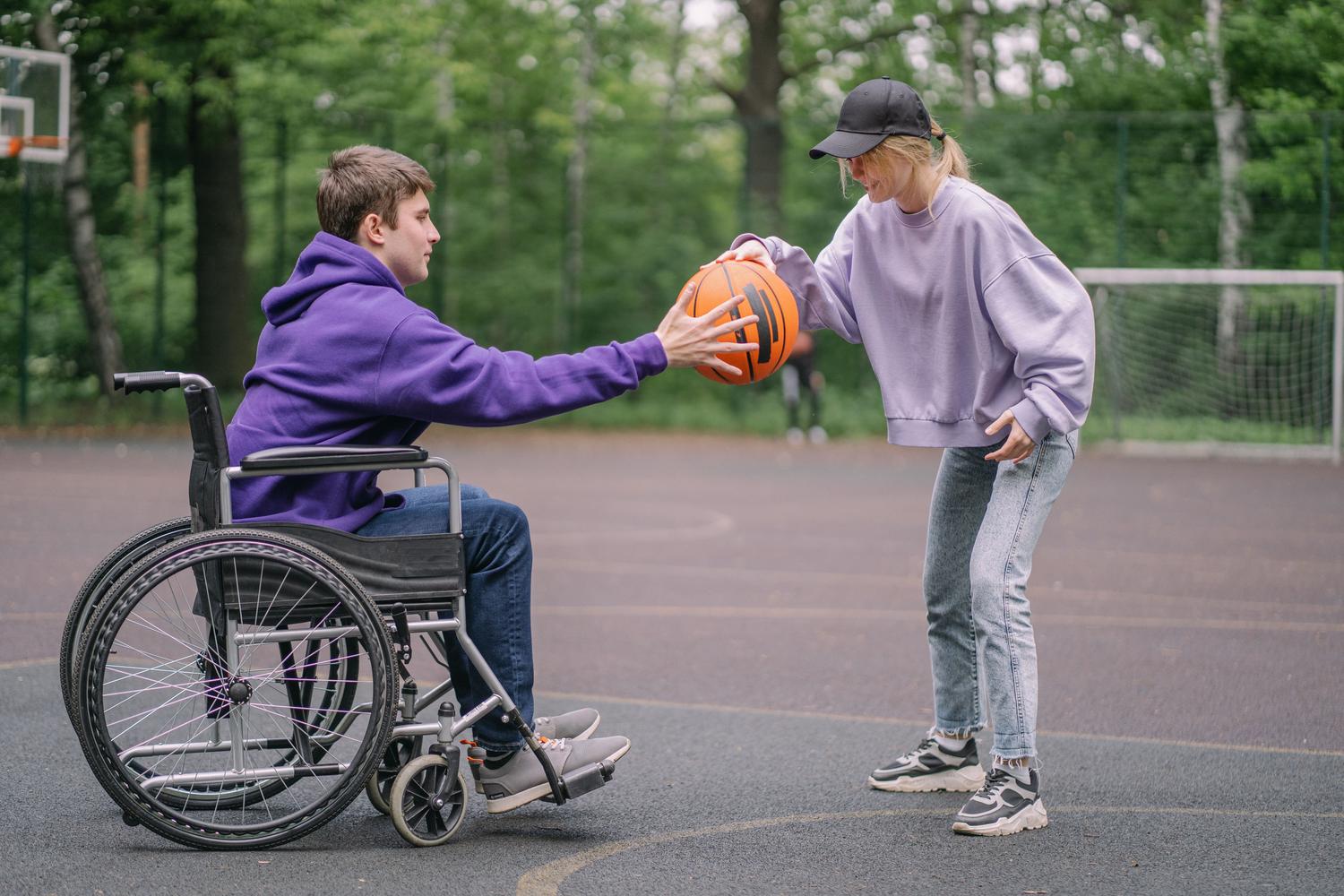 Persona en silla de ruedas jugando al baloncesto Persona en silla de ruedas jugando al baloncesto, demostrando que la actividad adaptada reduce la discapacidad y fomenta la participación.