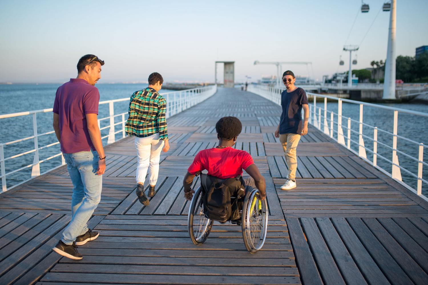 Grupo de amigos diversos Grupo de amigos diversos, incluyendo a una persona en silla de ruedas, paseando juntos, representando la inclusión social y la superación de la minusvalía.