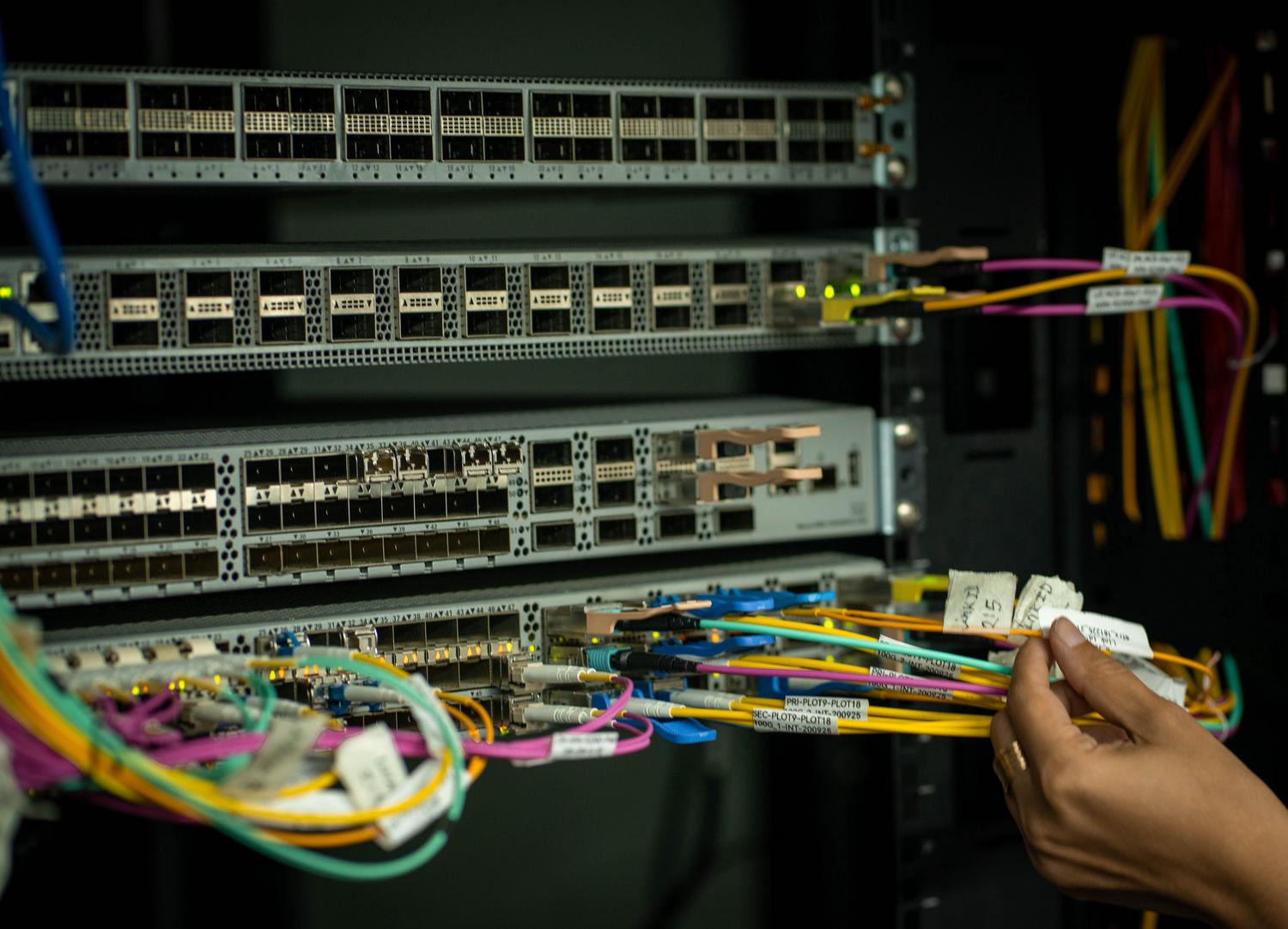 Técnico organizando cables de fibra óptica en un rack de servidores, ilustrando la infraestructura de red robusta. Técnico organizando cables de fibra óptica en un rack de servidores, ilustrando la infraestructura de red robusta.