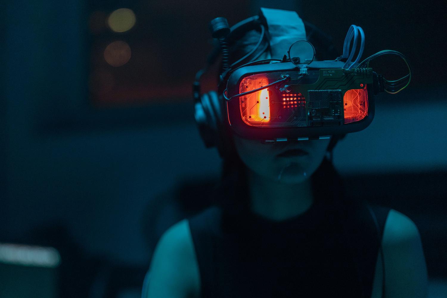 Mujer inmersa en una experiencia de realidad virtual con un casco de alta tecnología en una habitación oscura, representando la inmersión total. Mujer inmersa en una experiencia de realidad virtual con un casco de alta tecnología en una habitación oscura, representando la inmersión total.
