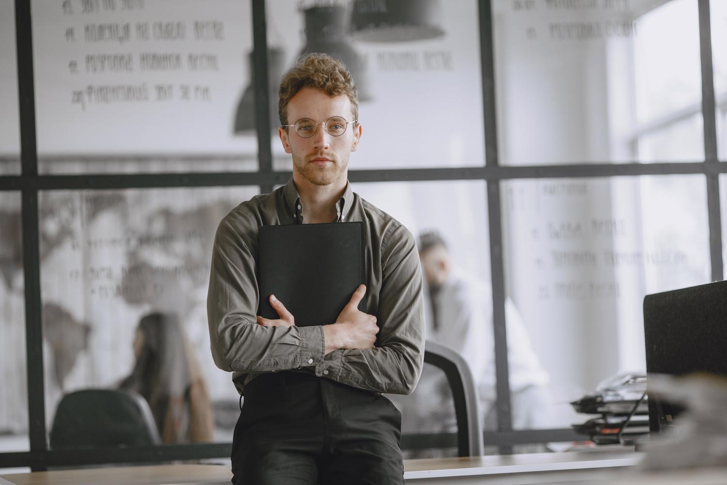 Trabajador joven y profesional en un entorno de oficina corporativa Trabajador joven y profesional en un entorno de oficina corporativa, ideal para ilustrar el inicio de la trayectoria laboral.