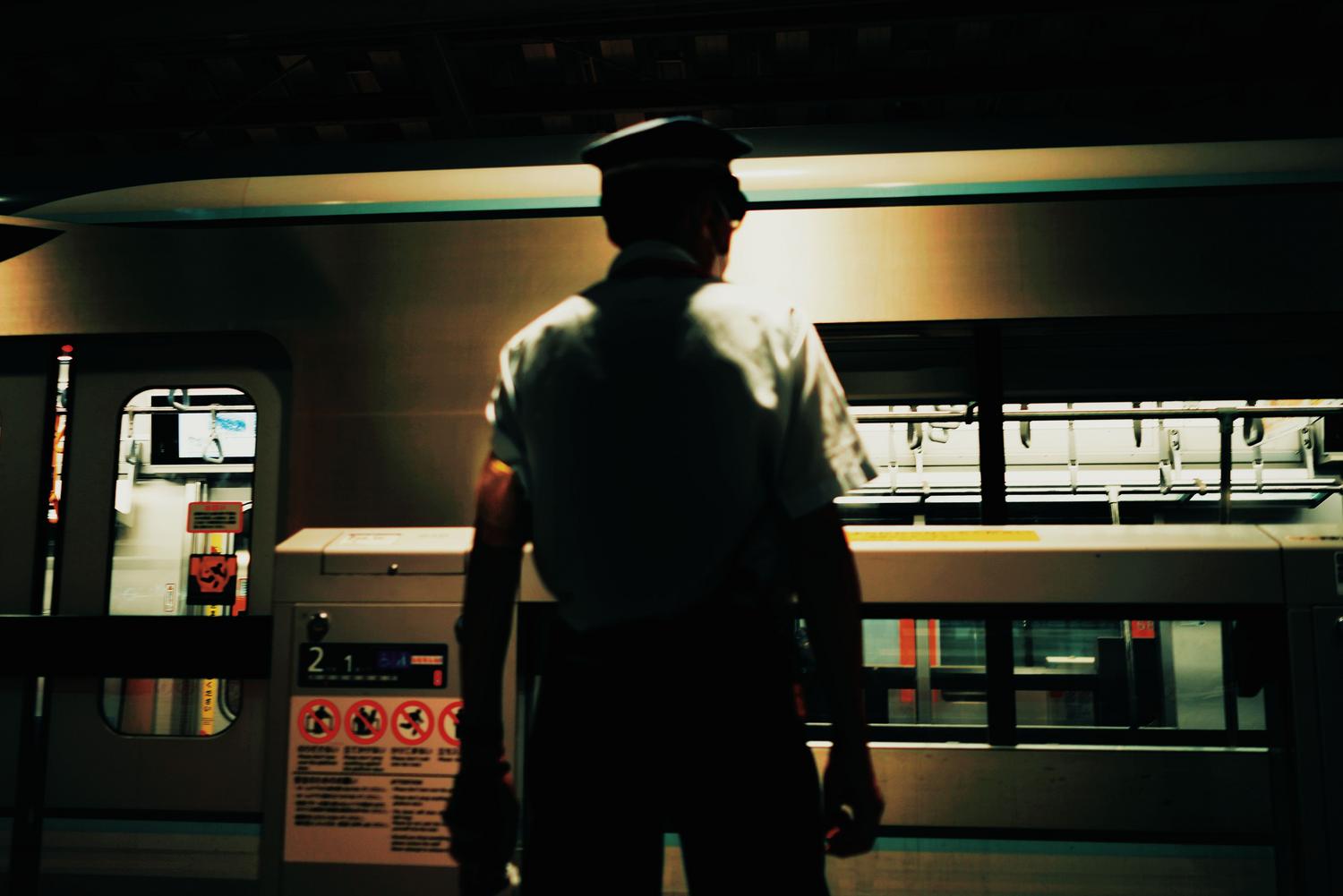 Trabajador de transporte público en el andén de un metro durante la noche, supervisando la llegada del tren. Trabajador de transporte público en el andén de un metro durante la noche, supervisando la llegada del tren.