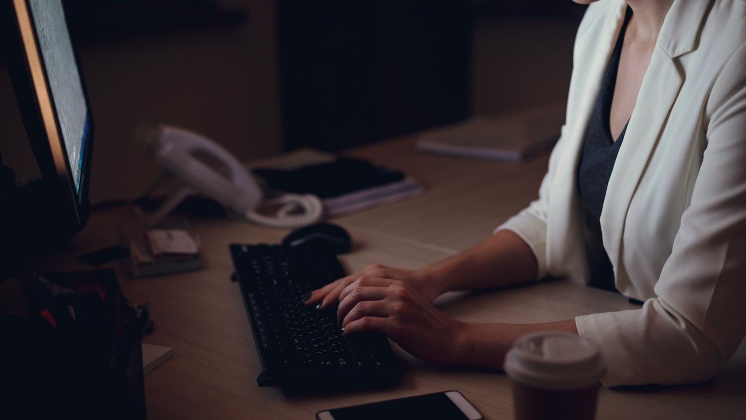 Mujer profesional trabajando en una oficina durante la noche, iluminada por el resplandor de la pantalla del ordenador. Mujer profesional trabajando en una oficina durante la noche, iluminada por el resplandor de la pantalla del ordenador.