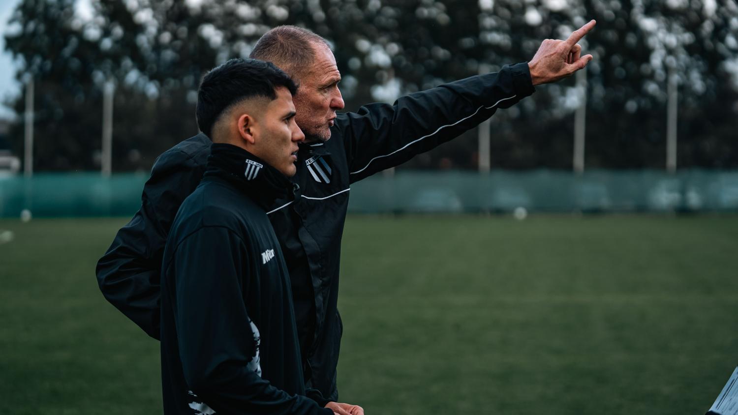 Entrenador de fútbol dando instrucciones a un jugador joven durante el entrenamiento Entrenador de fútbol dando instrucciones a un jugador joven durante el entrenamiento, simbolizando el alto rendimiento y la preparación física.