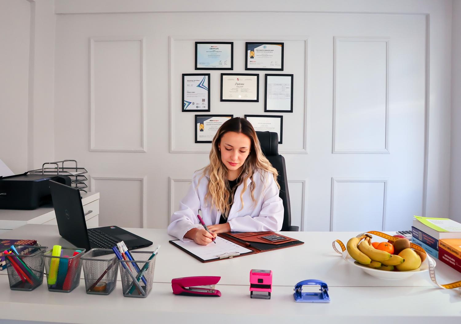 Nutricionista profesional en su despacho con diplomas y frutas, representando la cualificación académica del certificado de posgrado. Nutricionista profesional en su despacho con diplomas y frutas, representando la cualificación académica del certificado de posgrado.