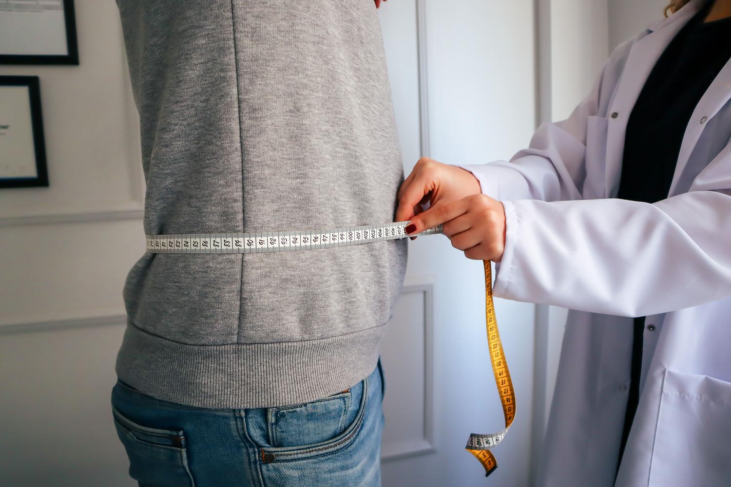 Nutricionista realizando una valoración antropométrica a un paciente en un entorno clínico. Nutricionista realizando una valoración antropométrica a un paciente en un entorno clínico.
