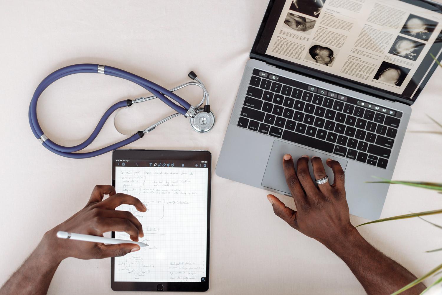 Formación online para profesionales de la salud Profesional de la salud utilizando una tablet y un portátil para investigación clínica.