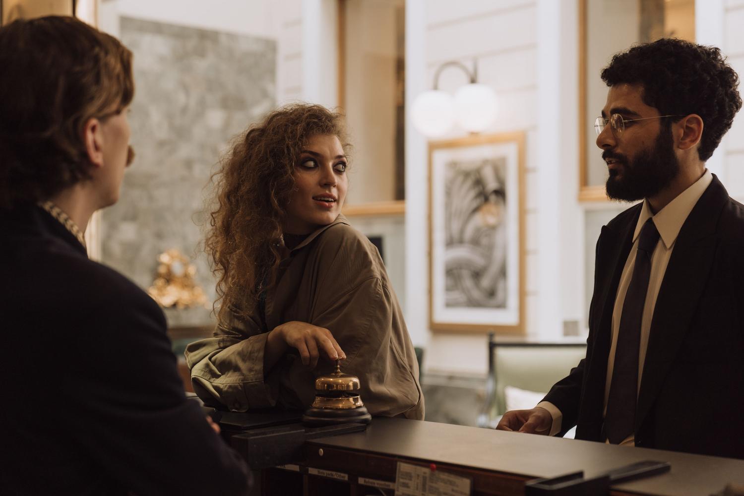 Interacción profesional entre clientes y personal en la recepción de un hotel, ilustrando la formación en Servicios de Restauración y Turismo Interacción profesional entre clientes y personal en la recepción de un hotel, ilustrando la formación en Servicios de Restauración y Turismo