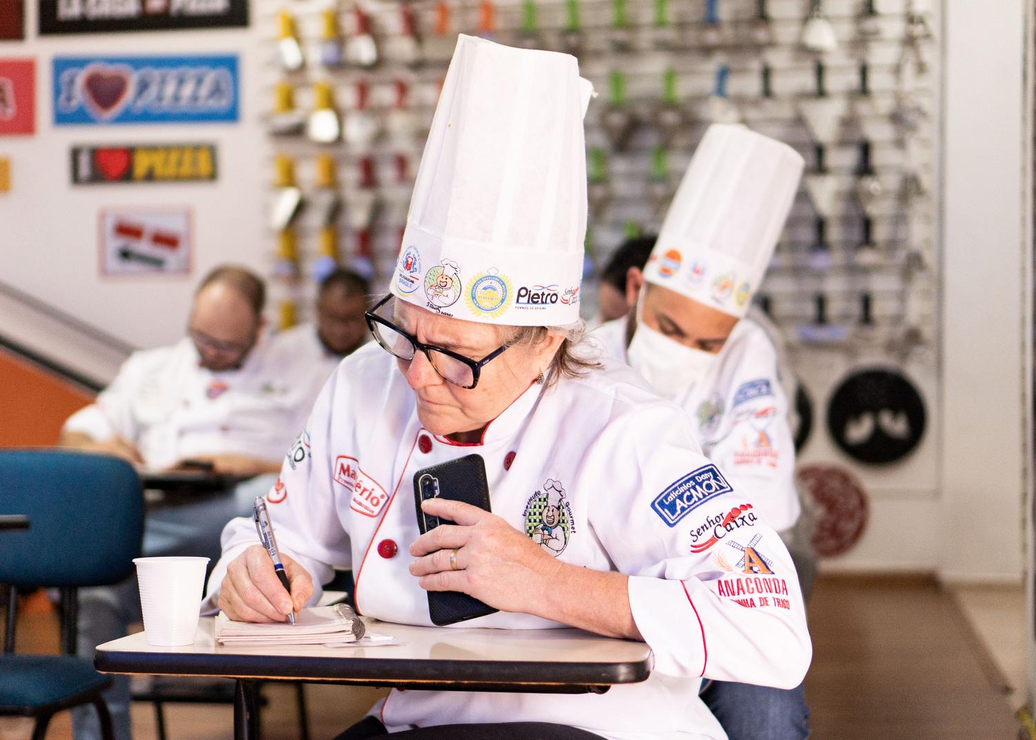 Estudiantes de cocina en una clase teórica tomando notas sobre técnicas culinarias Estudiantes de cocina en una clase teórica tomando notas sobre técnicas culinarias