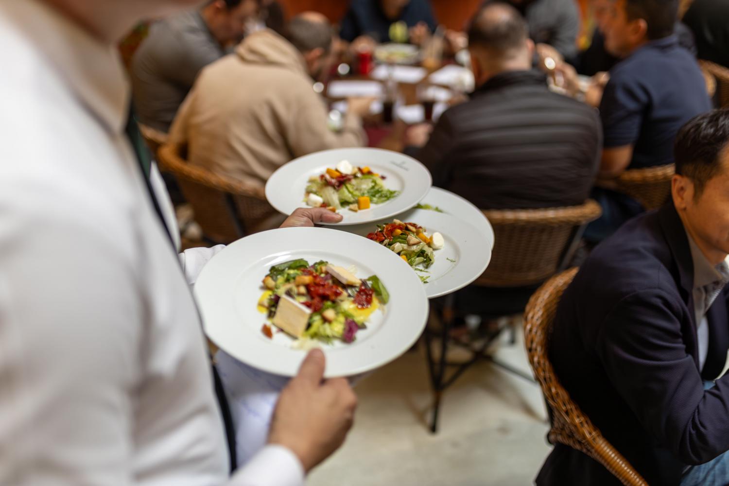 Camarero sirviendo ensaladas gourmet a clientes en un restaurante moderno Camarero sirviendo ensaladas gourmet a clientes en un restaurante moderno