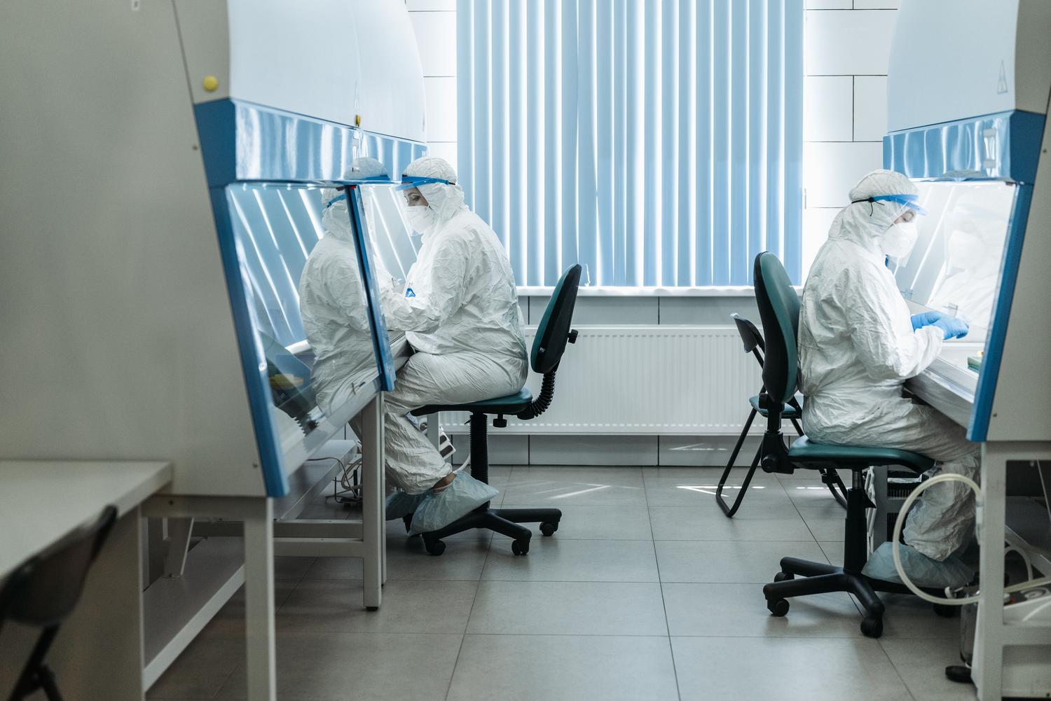 Bioseguridad en laboratorio Científicos con trajes de protección biológica completa trabajando en una sala blanca de laboratorio para garantizar la máxima bioseguridad.