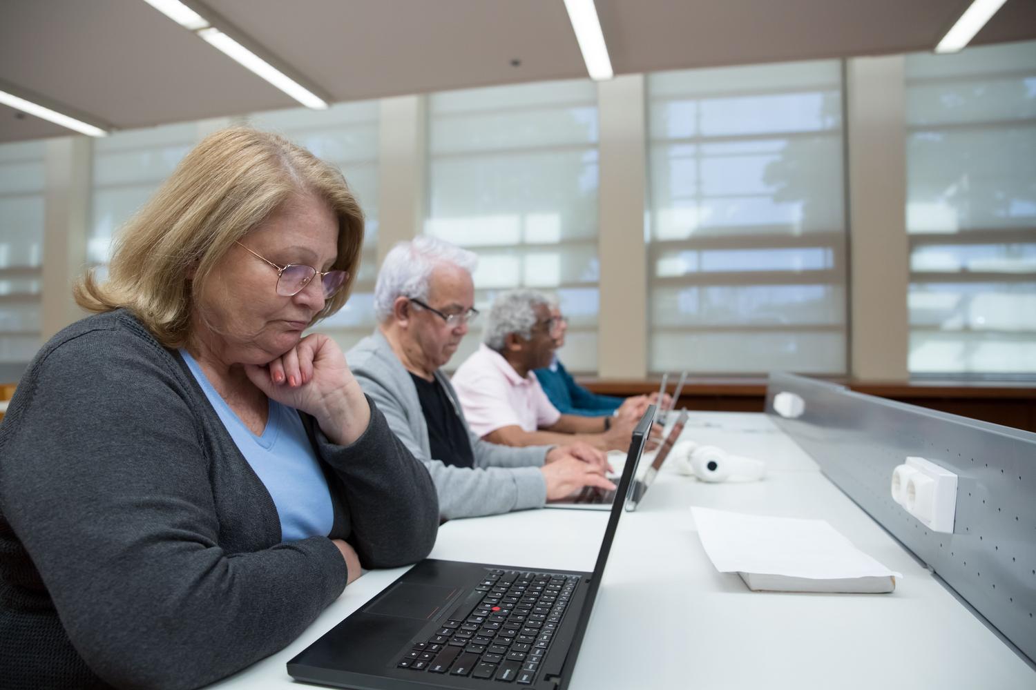 Adultos en un aula aprendiendo a usar ordenadores, representando la formación en TIC y la lucha contra la brecha digital. Adultos en un aula aprendiendo a usar ordenadores, representando la formación en TIC y la lucha contra la brecha digital.