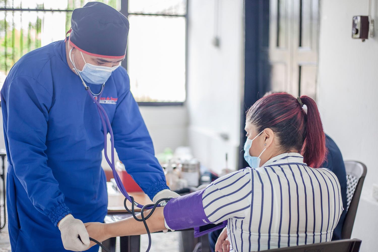 Profesional de enfermería tomando la tensión a un paciente Profesional de enfermería tomando la tensión a un paciente, ejemplificando las prácticas externas y los cuidados basados en la evidencia.
