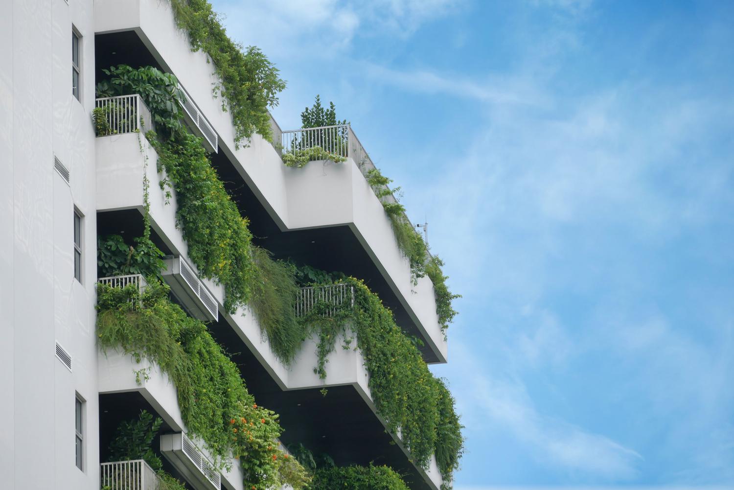 Edificio residencial moderno con jardines verticales en los balcones, simbolizando la sostenibilidad y el compromiso ambiental de la Comunidad Laudato Si'. Edificio residencial moderno con jardines verticales en los balcones, simbolizando la sostenibilidad y el compromiso ambiental de la Comunidad Laudato Si'.