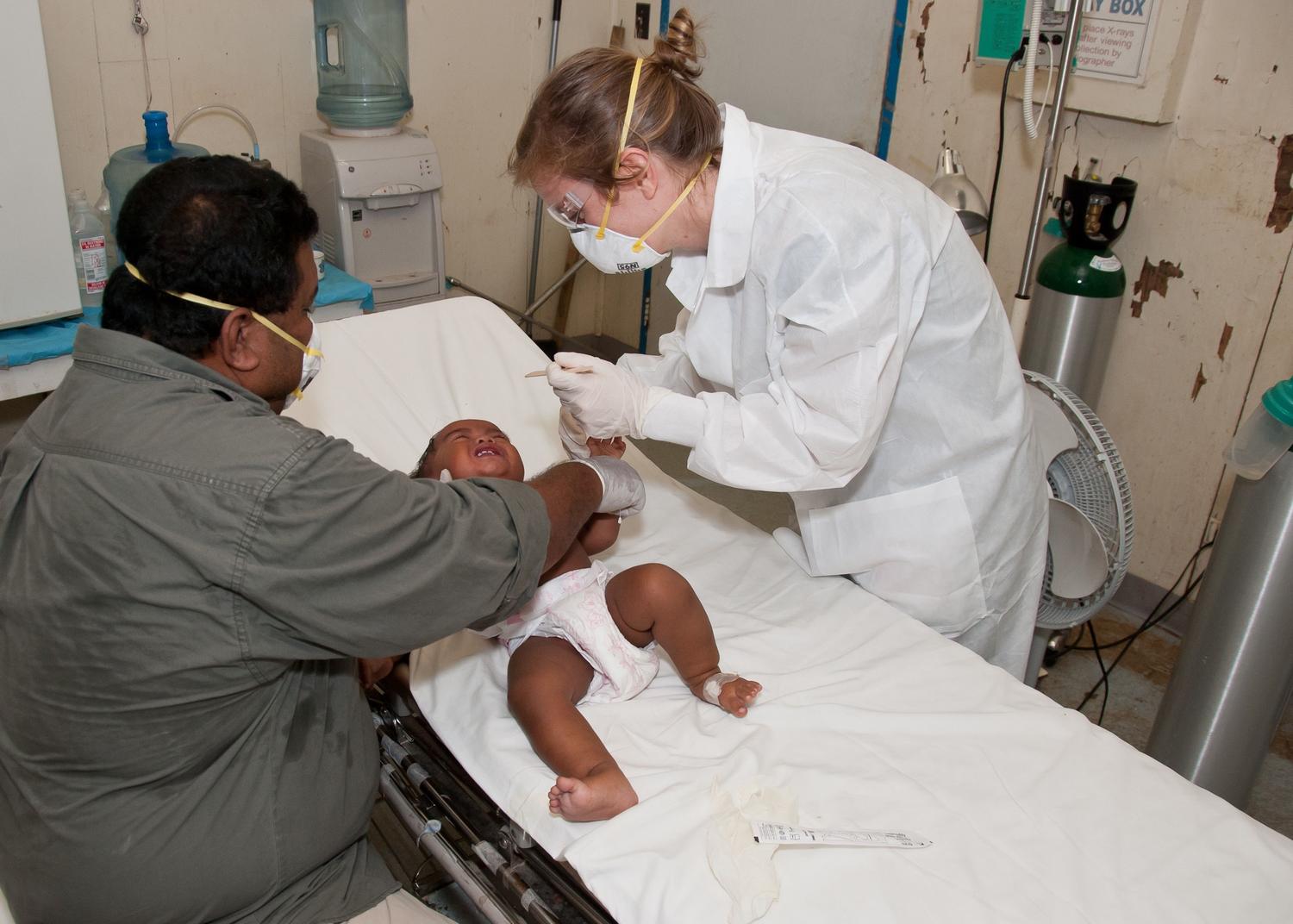 Médico especialista atendiendo a un bebé en situación crítica en una cama de hospital pediátrico. Médico especialista atendiendo a un bebé en situación crítica en una cama de hospital pediátrico.