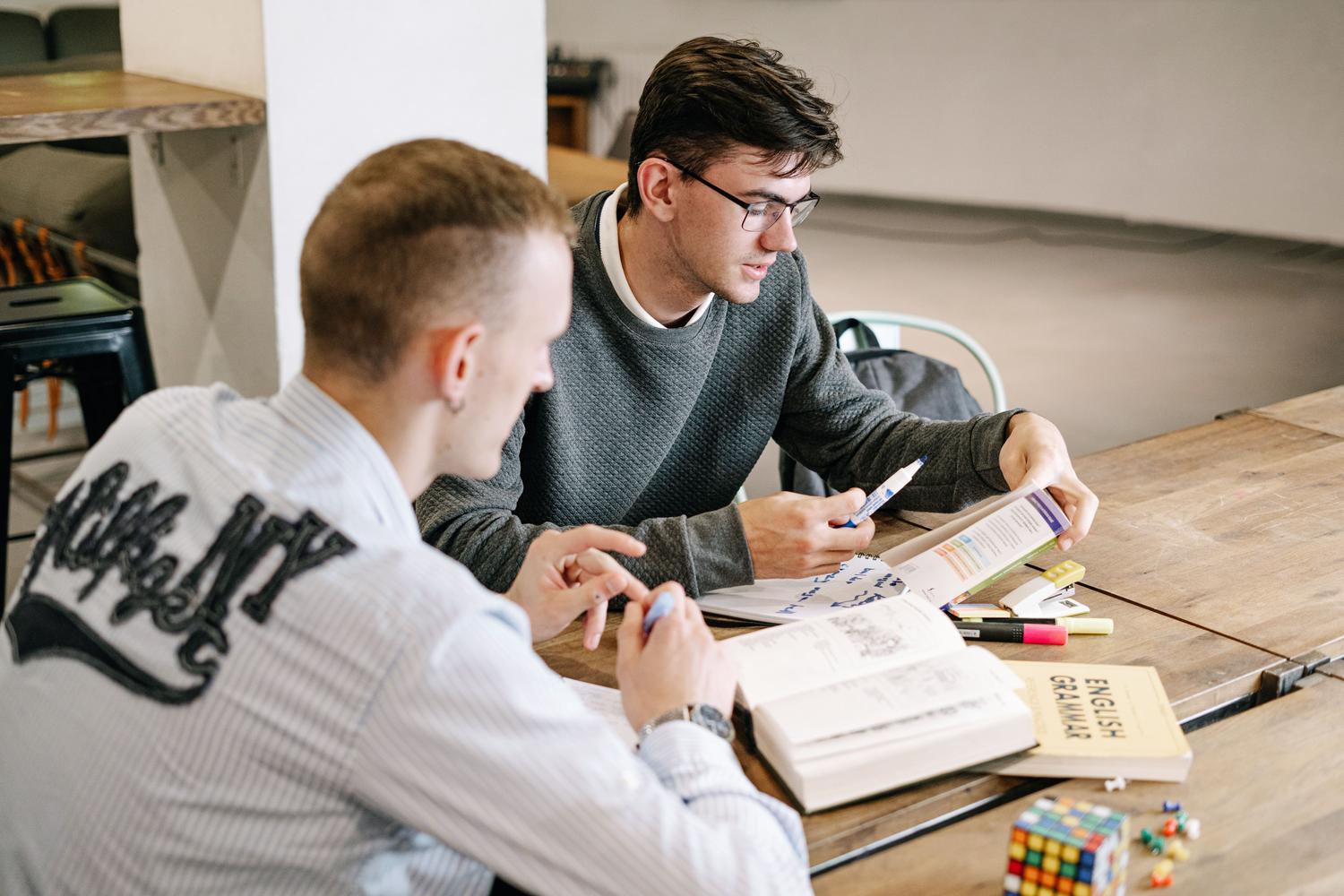 Dos estudiantes repasando libros de gramática inglesa Dos estudiantes repasando libros de gramática inglesa, ilustrando la fase de preparación para el Marlins Test.