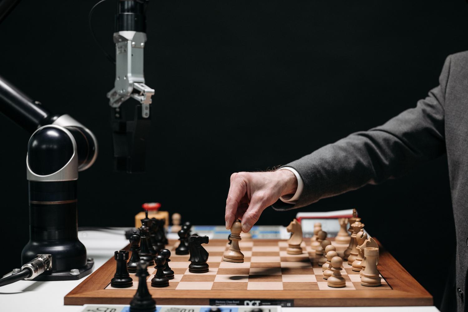Un brazo robótico juega al ajedrez contra un humano, simbolizando la innovación y la toma de decisiones estratégicas de la IA. Un brazo robótico juega al ajedrez contra un humano, simbolizando la innovación y la toma de decisiones estratégicas de la IA.