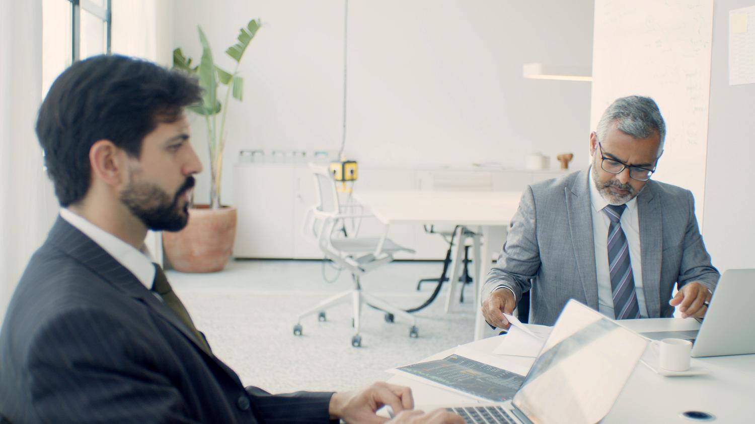 Empresarios trabajando con laptops en una oficina moderna, representando la implementación de soluciones de seguridad automatizadas. Empresarios trabajando con laptops en una oficina moderna, representando la implementación de soluciones de seguridad automatizadas.