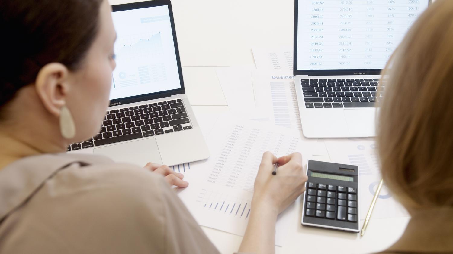 Profesionales analizando datos contables en ordenadores portátiles con el apoyo de una calculadora. Profesionales analizando datos contables en ordenadores portátiles con el apoyo de una calculadora.
