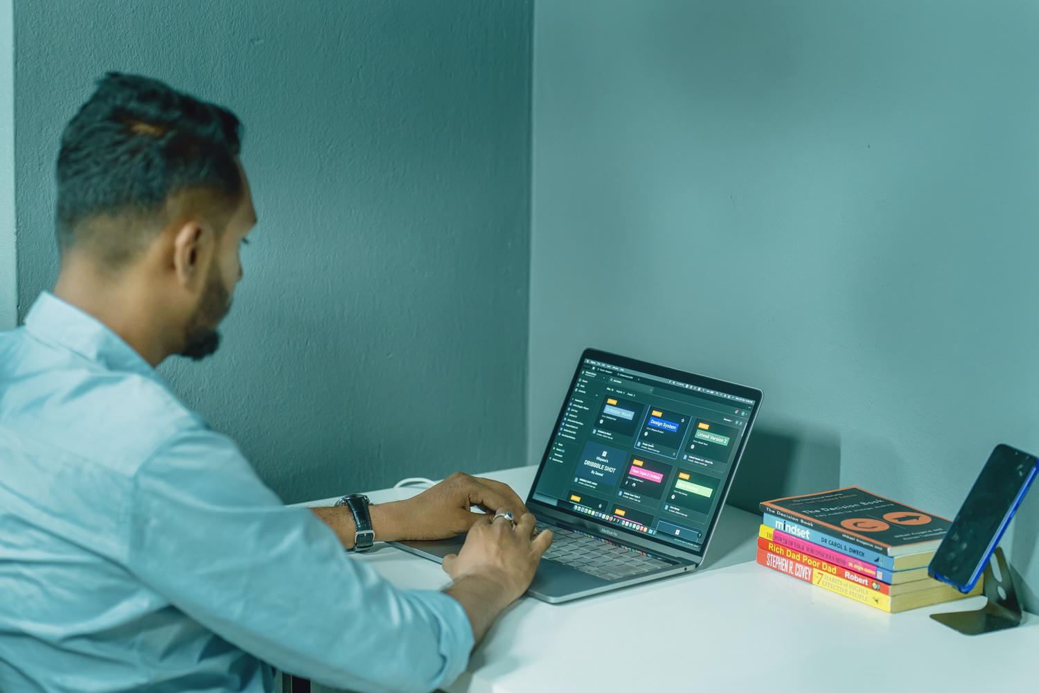 Hombre concentrado estudiando un curso de ofimática online en su oficina en casa, rodeado de libros de crecimiento profesional. Hombre concentrado estudiando un curso de ofimática online en su oficina en casa, rodeado de libros de crecimiento profesional.