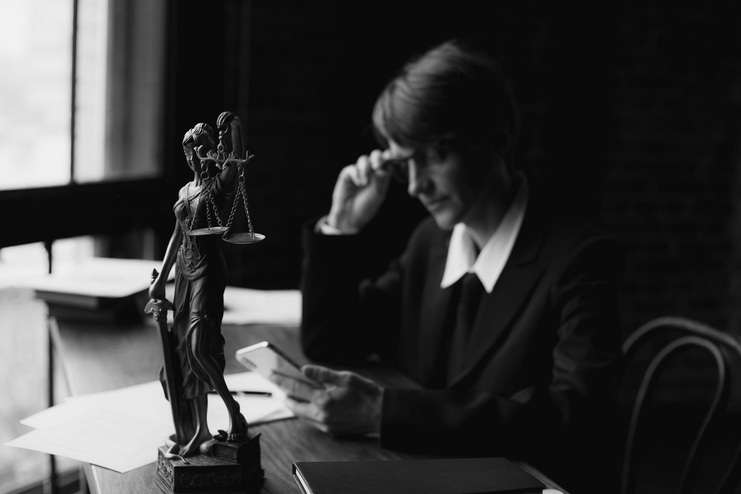 Representación del derecho digital: abogado utilizando un smartphone con la estatua de la Justicia al fondo en blanco y negro. Representación del derecho digital: abogado utilizando un smartphone con la estatua de la Justicia al fondo en blanco y negro.