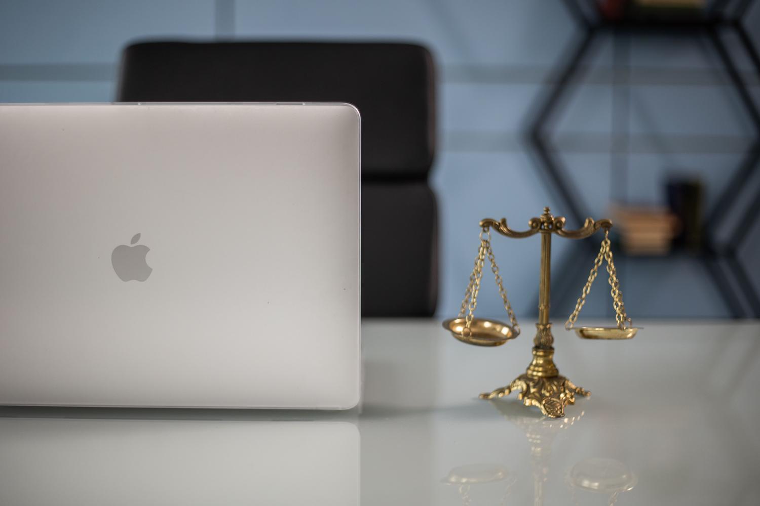 Equilibrio entre la tecnología y la justicia: una balanza junto a un ordenador portátil en un entorno de oficina moderno. Equilibrio entre la tecnología y la justicia: una balanza junto a un ordenador portátil en un entorno de oficina moderno.