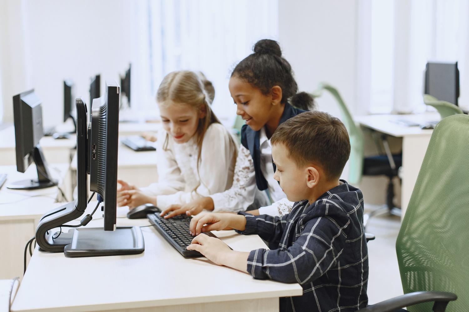 Niños de diversas procedencias aprendiendo programación en un laboratorio informático moderno. Niños de diversas procedencias aprendiendo programación en un laboratorio informático moderno.