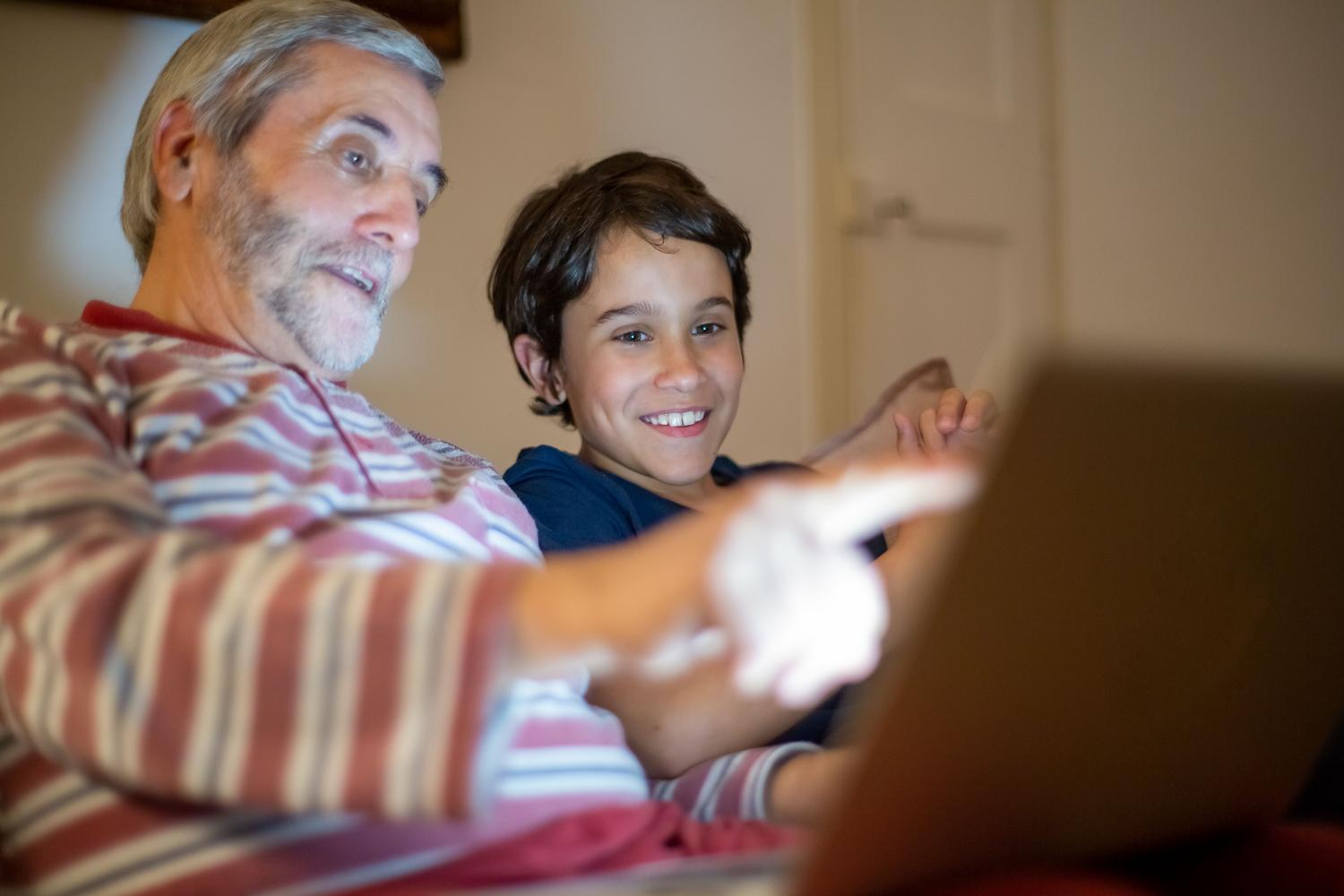 Un abuelo y su nieto compartiendo tiempo frente a un portátil, ilustrando la conexión generacional a través de la tecnología. Un abuelo y su nieto compartiendo tiempo frente a un portátil, ilustrando la conexión generacional a través de la tecnología.