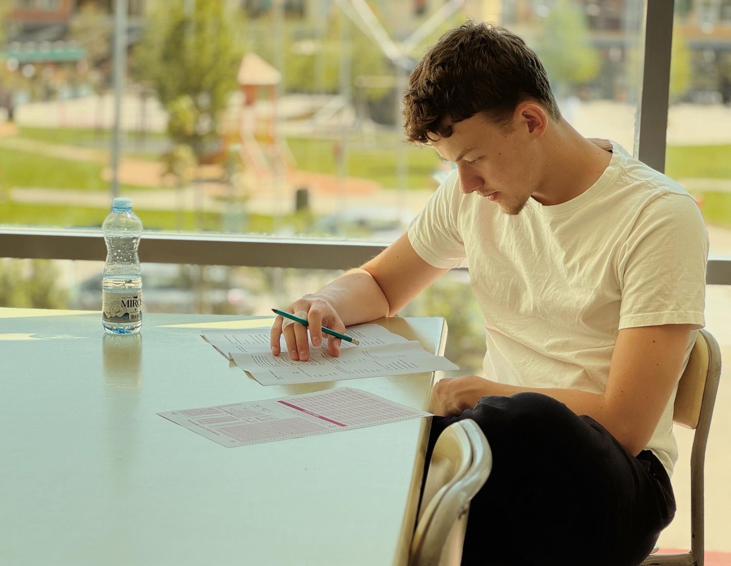 Joven concentrado estudiando atentamente con papeles y notas en una habitación iluminada, representando el enfoque del estudio tradicional. Joven concentrado estudiando atentamente con papeles y notas en una habitación iluminada, representando el enfoque del estudio tradicional.