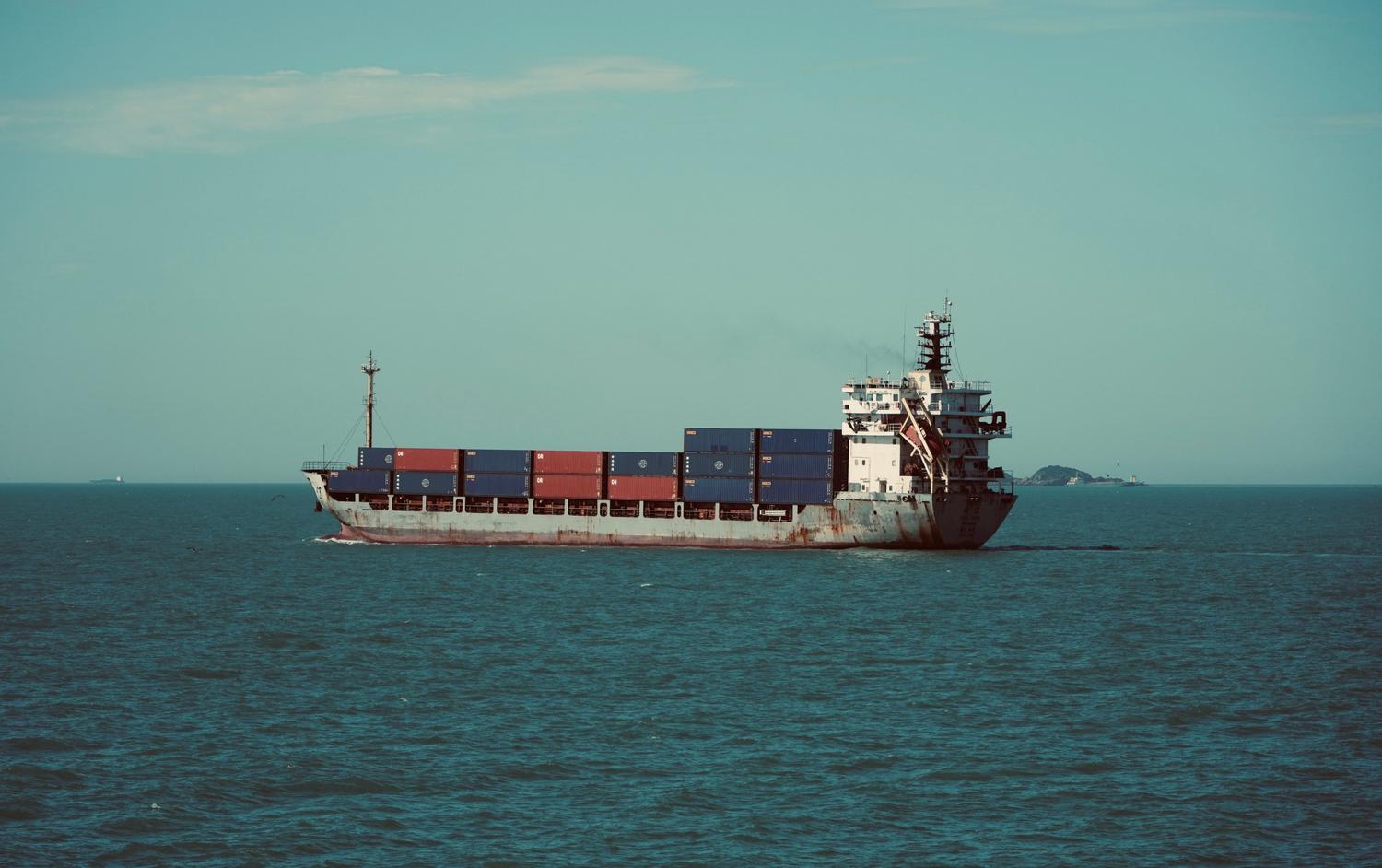 Buque de carga navegando en alta mar bajo un cielo despejado, simbolizando el comercio global. Buque de carga navegando en alta mar bajo un cielo despejado, simbolizando el comercio global.