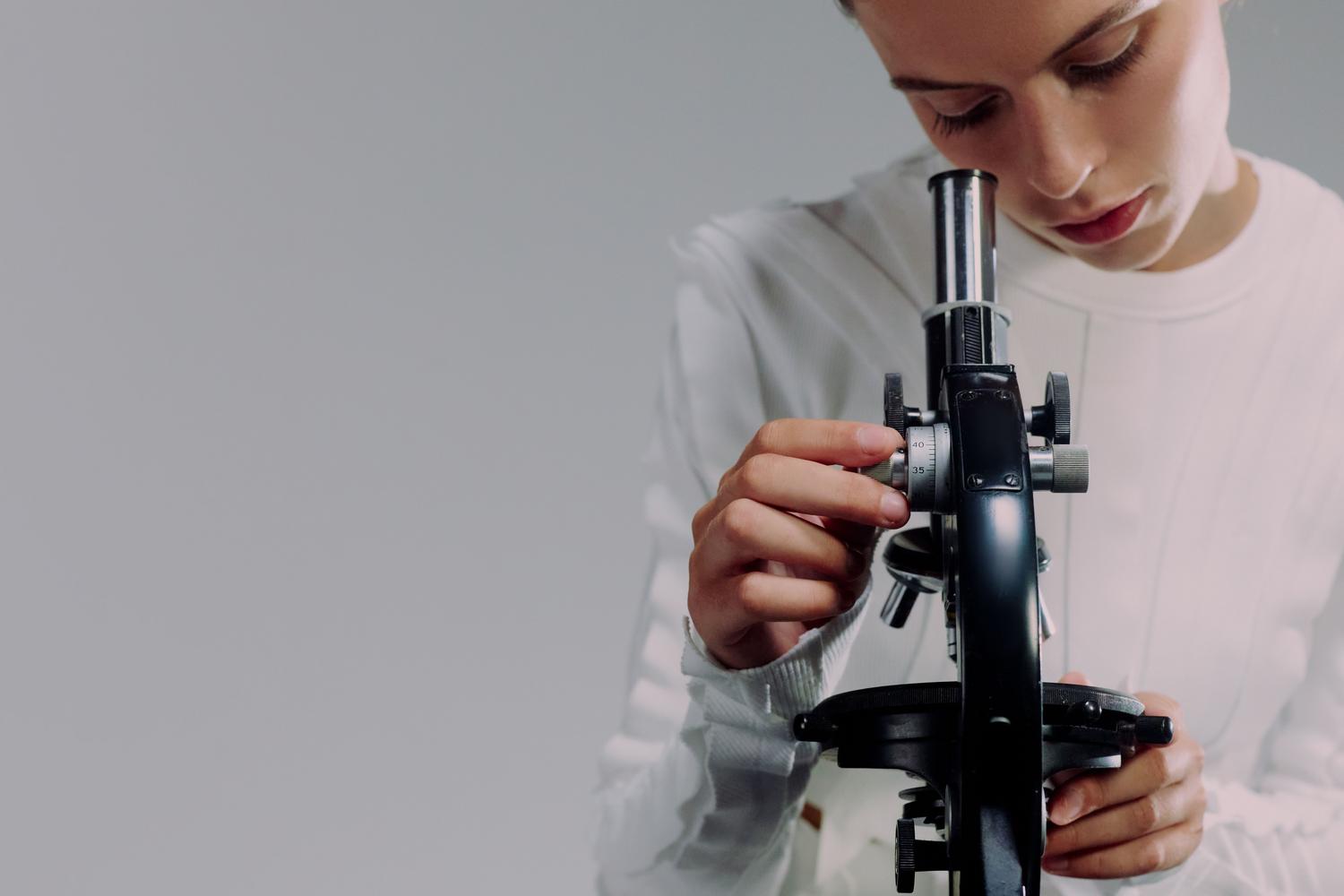Científica concentrada utilizando un microscopio, simbolizando la precisión en la investigación y la inclusión de género en STEM. Científica concentrada utilizando un microscopio, simbolizando la precisión en la investigación y la inclusión de género en STEM.
