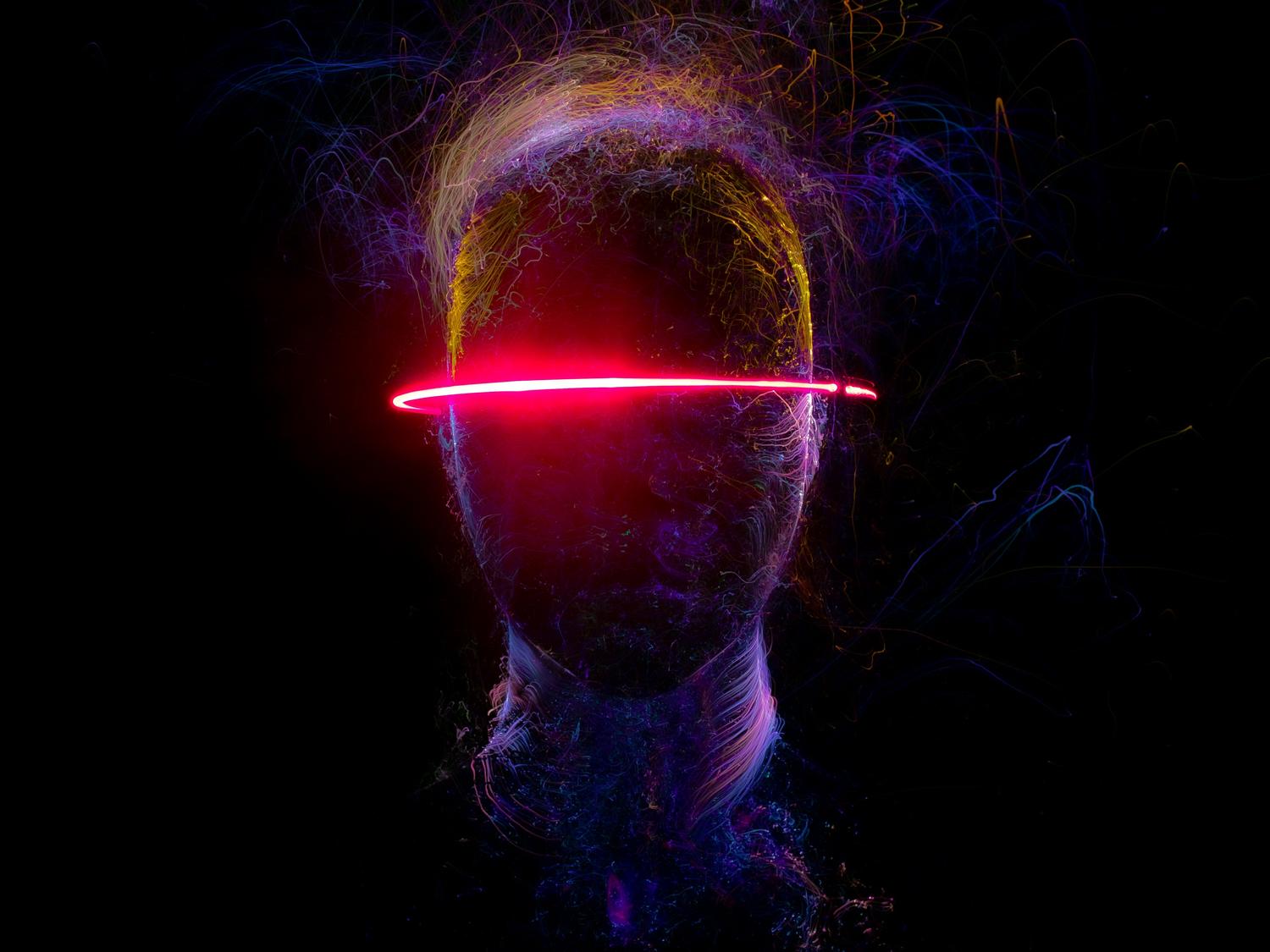 Representación conceptual de una cabeza humana con estelas de luz neón, simbolizando la neurotecnología y la interfaz cerebro-máquina. Representación conceptual de una cabeza humana con estelas de luz neón, simbolizando la neurotecnología y la interfaz cerebro-máquina.