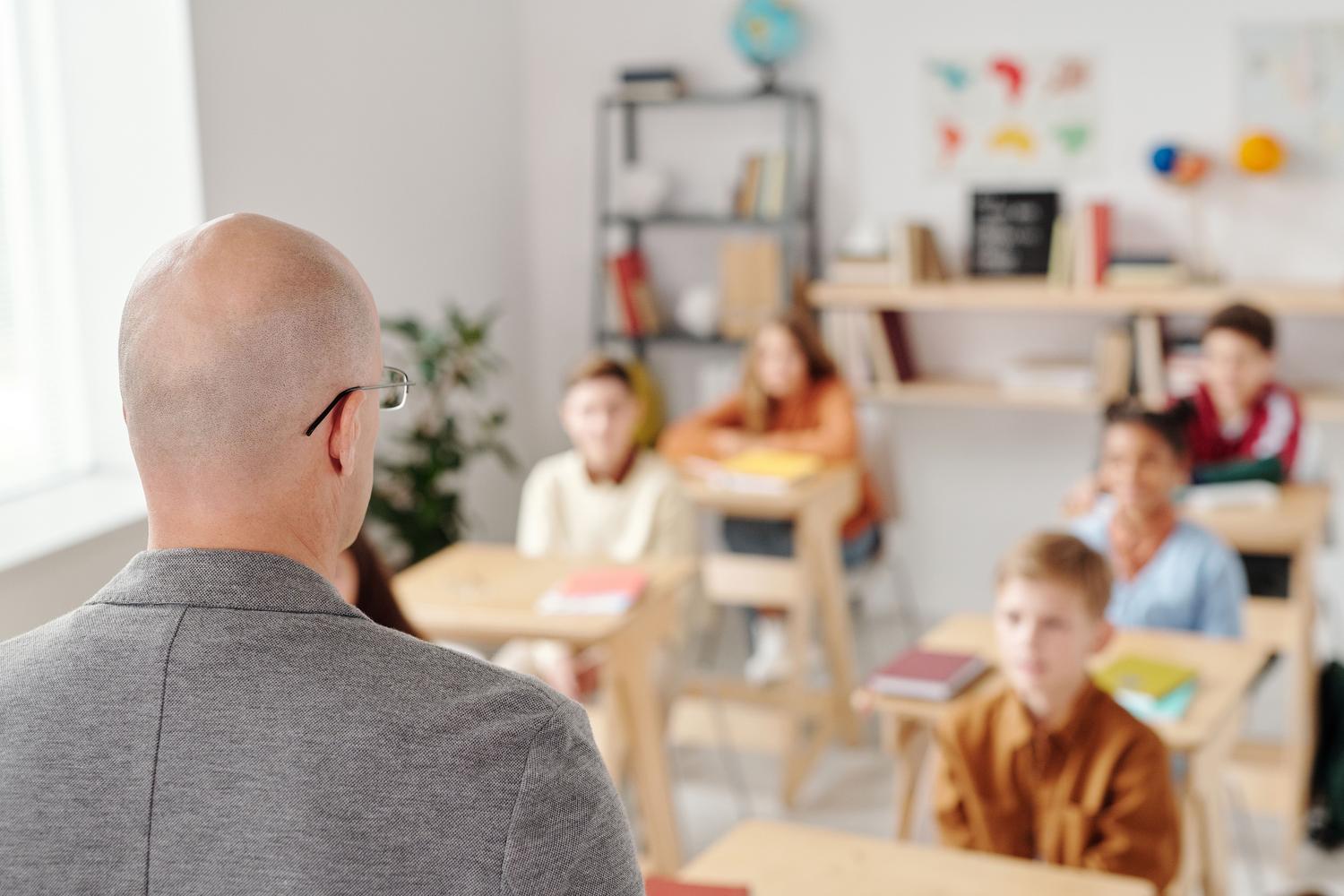 Teacher giving a class in a classroom with attentive students, illustrating the goal of accessing the public teaching service. Teacher giving a class in a classroom with attentive students, illustrating the goal of accessing the public teaching service.