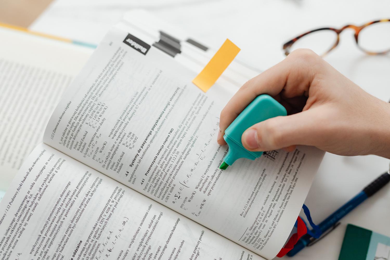 Close-up of a hand highlighting a textbook with a fluorescent marker, detailing the meticulous organization of the study. Close-up of a hand highlighting a textbook with a fluorescent marker, detailing the meticulous organization of the study.