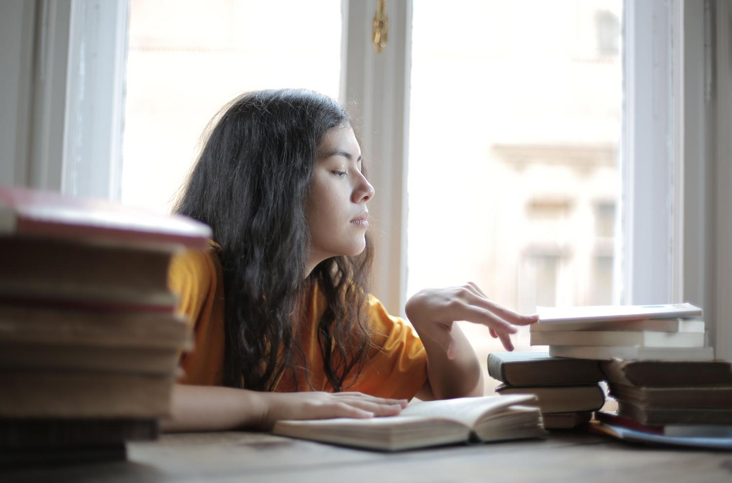 Aspirante a profesor de secundaria estudiando Aspirante a profesor de secundaria estudiando concentrada con libros, representando el esfuerzo para sumar puntos en méritos y cursos.