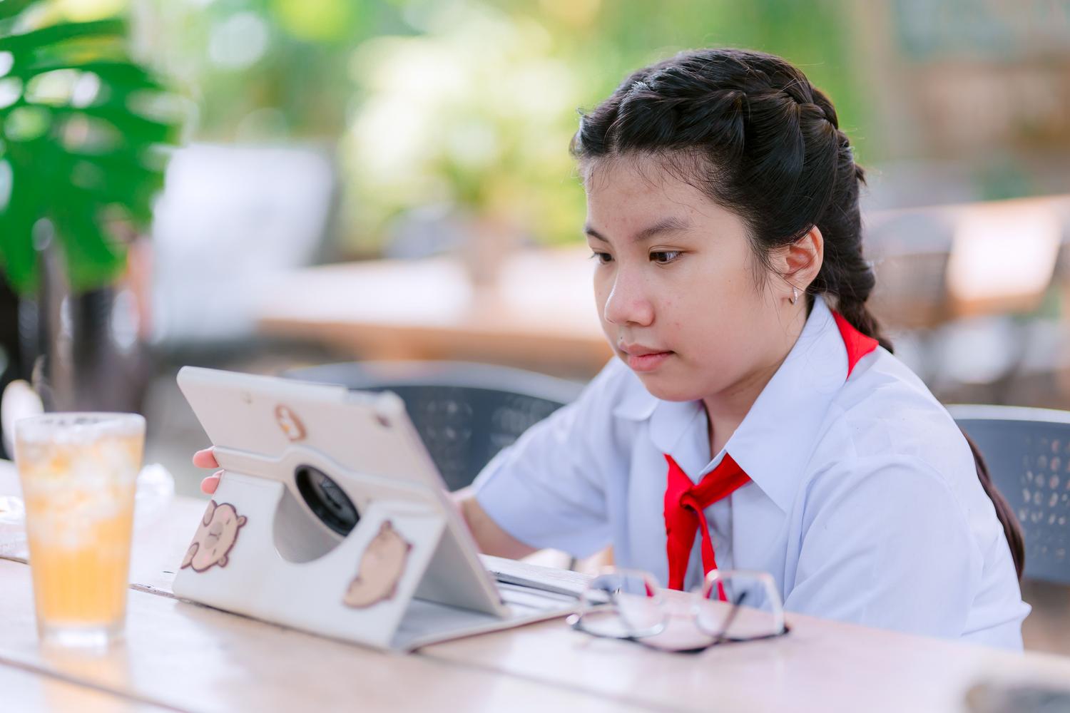 Estudiante utilizando una tablet para estudiar en un entorno moderno, representando la integración de las TIC y los recursos digitales en la enseñanza de las matemáticas. Estudiante utilizando una tablet para estudiar en un entorno moderno, representando la integración de las TIC y los recursos digitales en la enseñanza de las matemáticas.