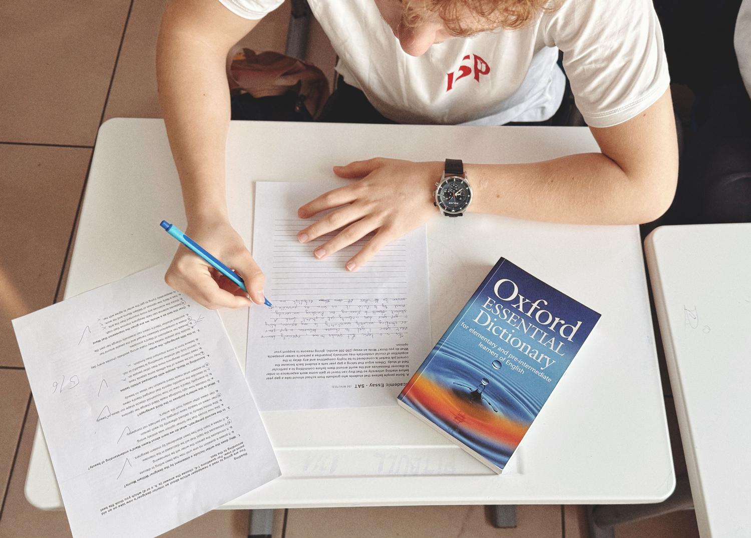 Student taking an English exam with an Oxford dictionary on the table Student taking an English exam with an Oxford dictionary on the table