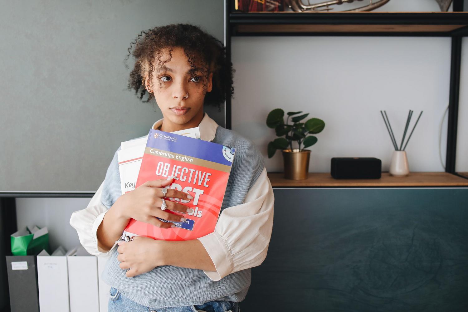 Young woman holding Cambridge English certification books Young woman holding Cambridge English certification books