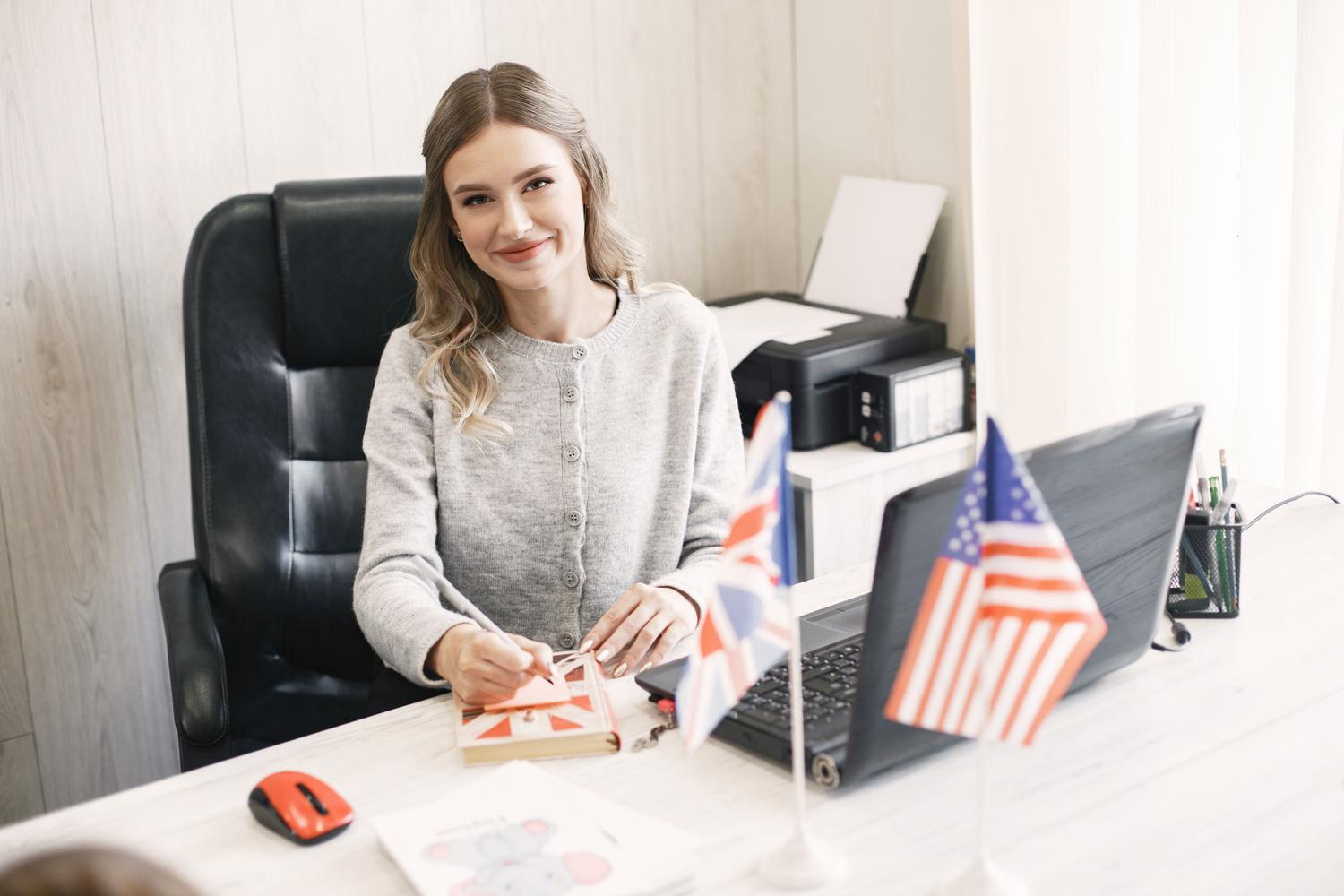Professional woman at her desk with UK and US flags, representing business English Professional woman at her desk with UK and US flags, representing business English