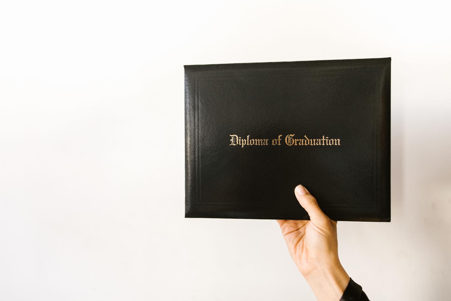 Close-up of a hand holding a graduation diploma with elegant typography Close-up of a hand holding a graduation diploma with elegant typography