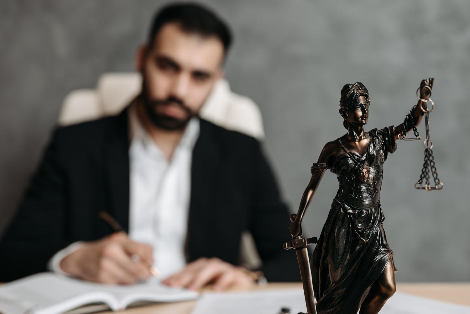 Profesional del derecho trabajando en su despacho con la figura de la justicia en primer plano, representando el cumplimiento de los deberes judiciales. Profesional del derecho trabajando en su despacho con la figura de la justicia en primer plano, representando el cumplimiento de los deberes judiciales.