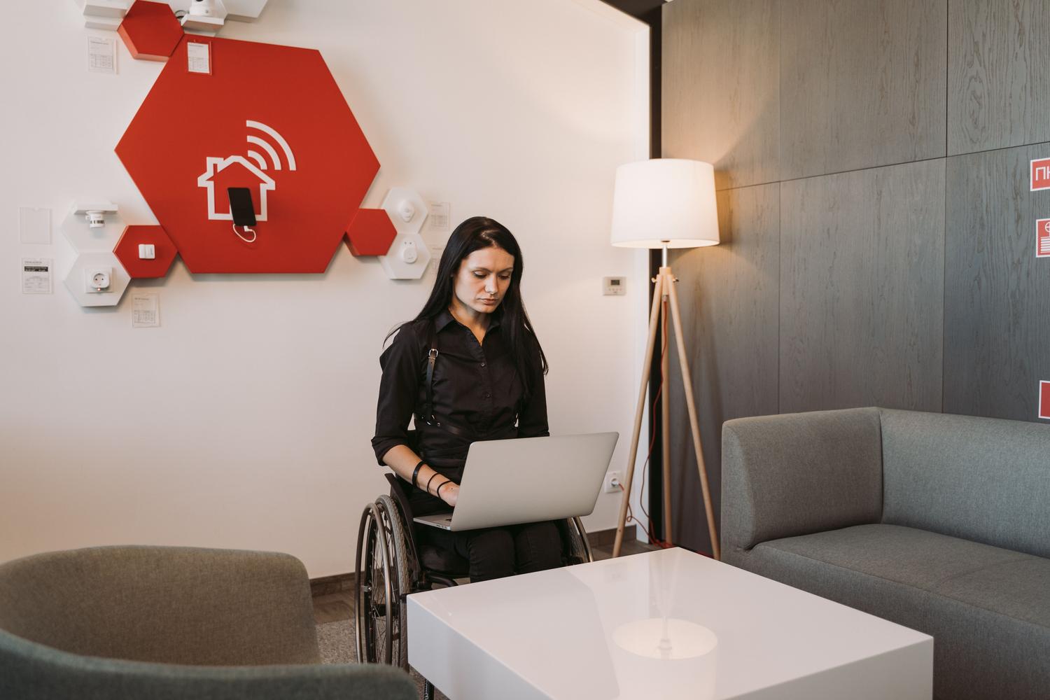 Persona en silla de ruedas utilizando tecnología en un entorno accesible, representando la domótica y la autonomía personal. Persona en silla de ruedas utilizando tecnología en un entorno accesible, representando la domótica y la autonomía personal.