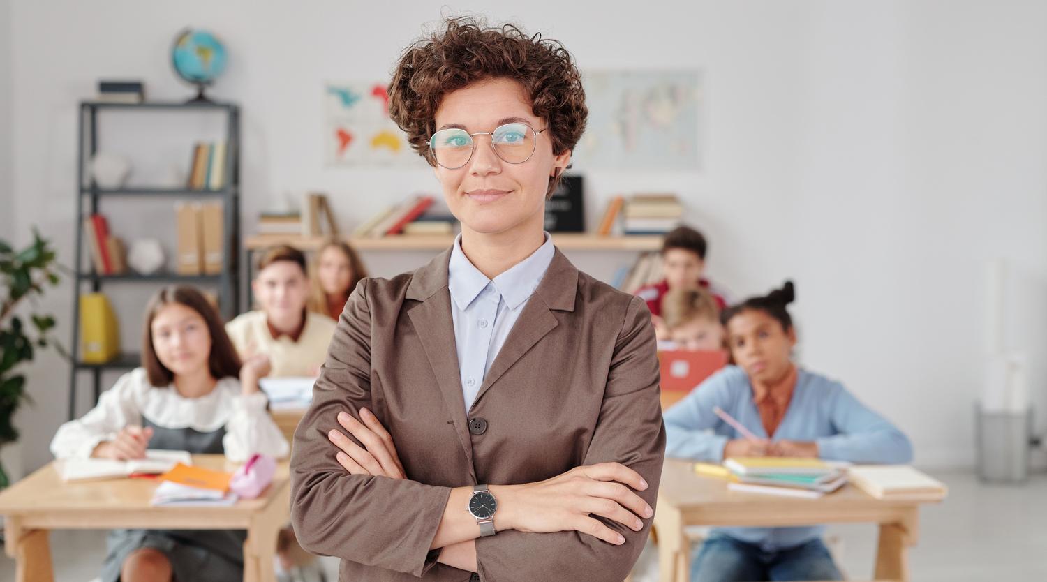 Docente con actitud de liderazgo en el aula, representando el perfil de líder pedagógico del cuerpo de inspección. Docente con actitud de liderazgo en el aula, representando el perfil de líder pedagógico del cuerpo de inspección.